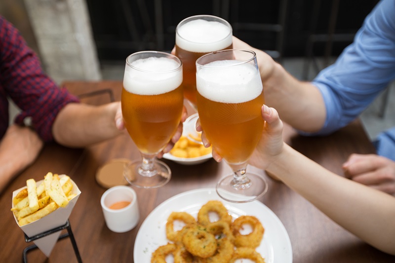 Amigos bebiendo cerveza y comiendo en un bar.